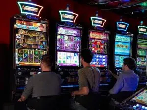 Tre män framför spelmaskiner i ett landbaserat casino